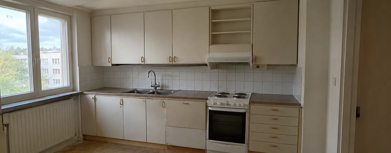 Före: ett kök längs en vägg med vita skåpluckor och trähandtag, vitt kakel, laminatbänk, en fristående spis med plattor och en öppen hylla ovanför fläkten.